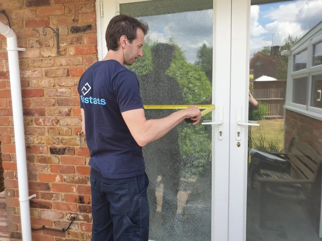 man measuring glass door